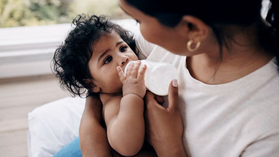 Close-up of a mother feeding her baby with a bottle.