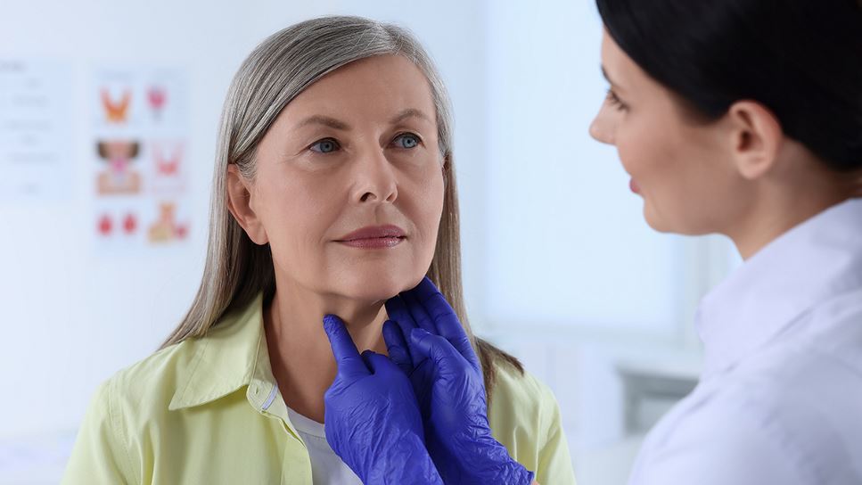 An endocrine specialist is checking the thyroid gland of an elderly woman who suspects she may have a thyroid disease or disorder.