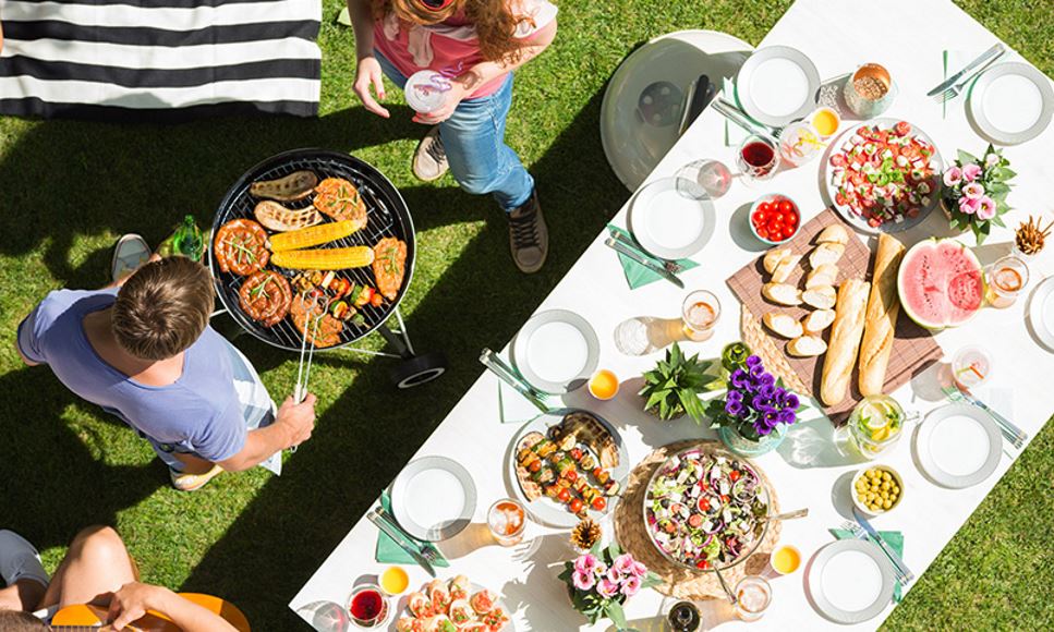 friends grilling vegetables and setting a picnic table